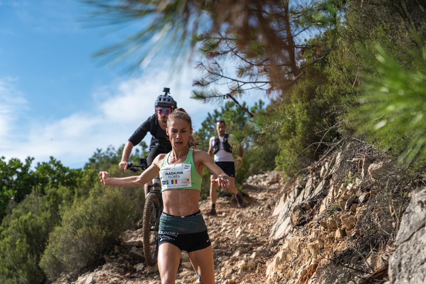 Trail-Läuferin Madalina Florea bei der Trail World Series, verfolgt von Mountainbiker